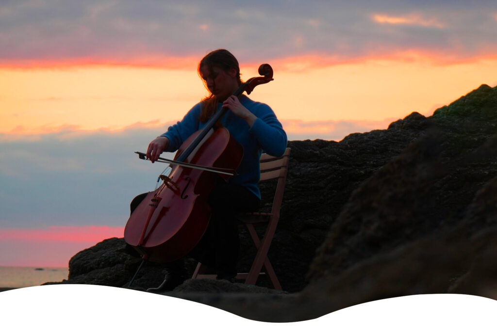 Musicienne jouant du violoncelle en plein air au coucher du soleil, lors d’un concert intimiste des Rencontres du Littoral.