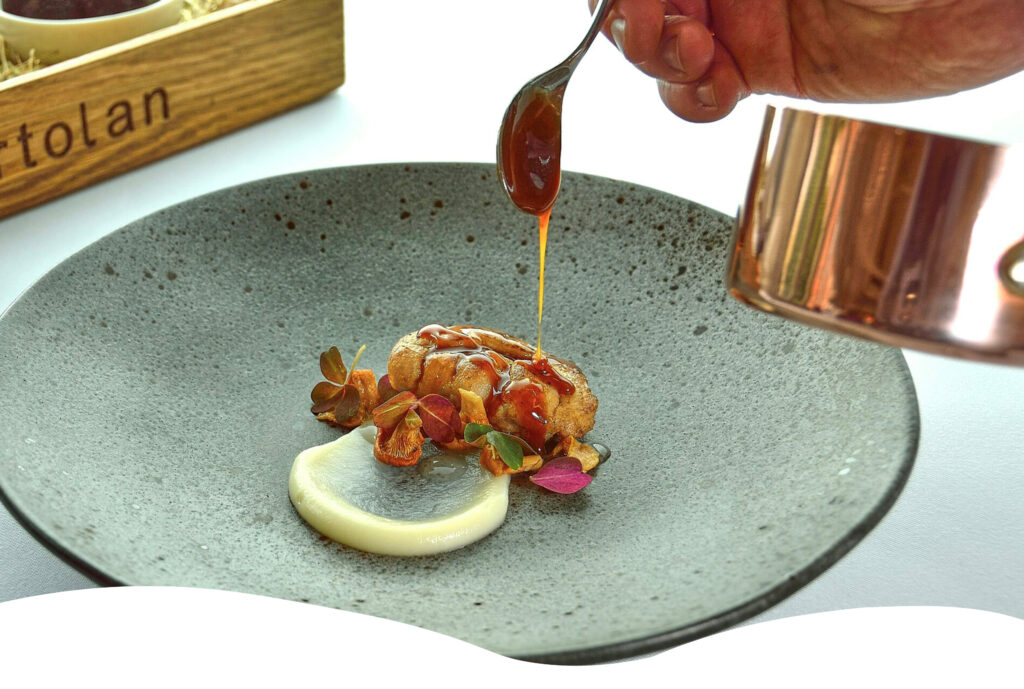 Sauce versée sur un plat gastronomique raffiné, illustrant le thème “L’Océan & La Table” lors des Rencontres du Littoral.